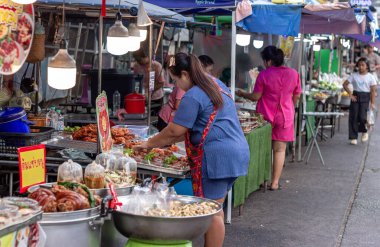 Suratthani, Tayland - 21 Nisan 2024: Yemek ve sebze almak için sokaklarda yürüyen insanlar, hem Tayland 'ın şehir ve kırsal kesimlerinde hem de sokak yemeklerinde yol kenarında satılıyor.