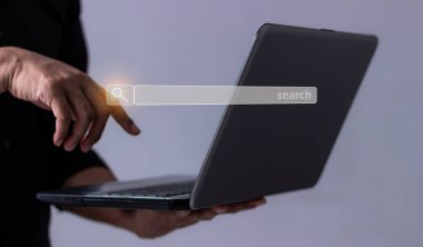 Dizüstü bilgisayarlı genç adam arama çubuğuna dokunuyor, arama işi