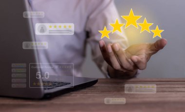 Mükemmellik İncelemesi, dizüstü bilgisayarlı genç adam incelenmek için beş yıldız tutuyor ve 5 yıldız veriyor. Hizmette çok iyi sonuçlar veriyor. İyi değerlendirme 5 yıldız değerlendirmesi, bulanık bir arka plan.