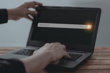 Dizüstü bilgisayarlı genç adam arama çubuğuna dokunuyor, arama işi