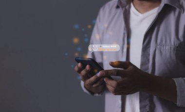 Değerlendirme: Genç Adam 5 yıldızlı akıllı telefonu değerlendirmek için kullanıyor ve 5 yıldız veriyor. Hizmette çok iyi sonuçlar veriyor.