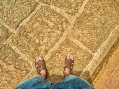 POV bakış açısı: Barichara, Santander, Kolombiya 'nın kaldırımlı yolunda duran mavi kot pantolonlu ve sandaletli ayaklar. Kolombiya 'da yürüyüş ya da yürüyüş turizmi