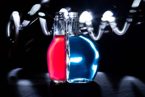 Beleuchtete Gläser Auf Schwarzem Hintergrund Flaschen Mit Farbiger Flüssigkeit Inneren — Stockfoto