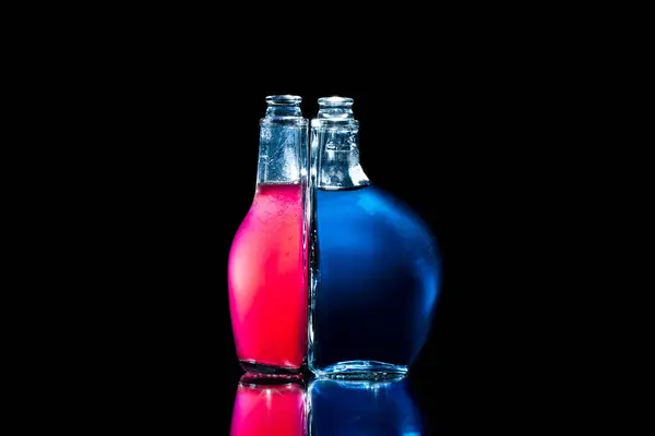 黒い背景に照らされた瓶 中着色された液体が付いているびん — ストック写真