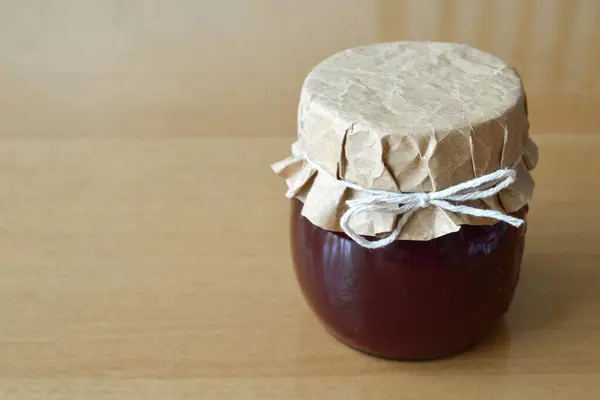 Home-made plum jam in the jar on the wooden table with copy space