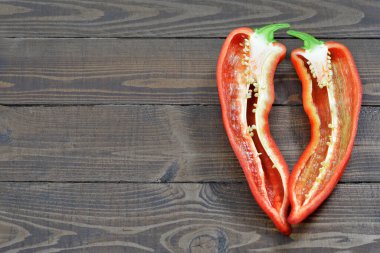 Taze kırmızı biber, ahşap arka planda ikiye bölünmüş, fotokopi alanı ile.