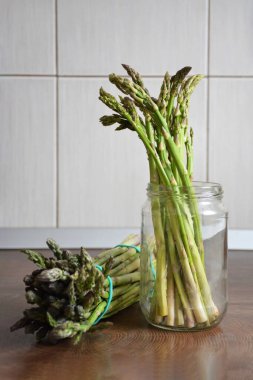 Mutfak tahtasında bir sürü yeşil kuşkonmaz var.