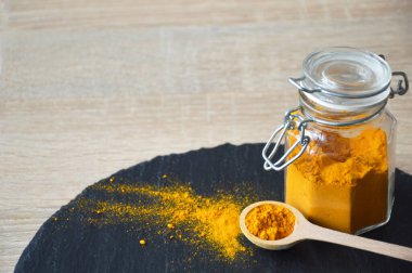 Tahta kaşıkta siyah tahtada zerdeçal tozu, yakın çekim