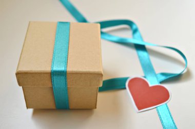 Sevgililer Günü konsepti, beyaz ahşap arka planda kırmızı kalp sembolü olan hediye kutusu.