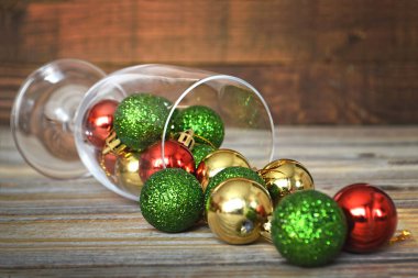 Ahşap arka planda büyük şarap kadehinde parlayan Noel topları. Noel ve Yeni Yıl kavramı.
