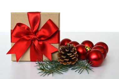 Kırmızı kurdele, çam kozalağı ve parlak toplarla sarılmış Noel hediyesi. 