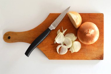 Mutfak masasında dilimlenmiş soğan ve bıçak, üst manzara. 