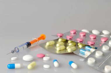 Gri arka planda şırınga, hap, tablet ve kapsüller