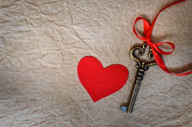 Grunge kağıt arka planında kırmızı kumaş kalp ve anahtar