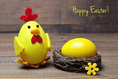 Mutlu Paskalya kartları: oyuncak piliç ve yuvadaki sarı boyalı yumurta.