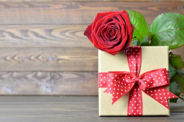 Sevgililer Günü hediyesi ve ahşap arka planda kırmızı gül.