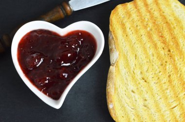 Kalp şeklinde kasede çilek reçeli ve tost.