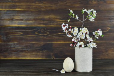 Tahta Paskalya yumurtası ve vazodaki bahar çiçekleri.