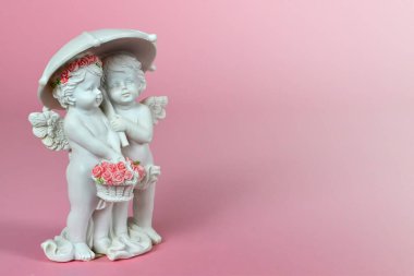 Pembe arka planda şemsiye altında iki melek figürü 
