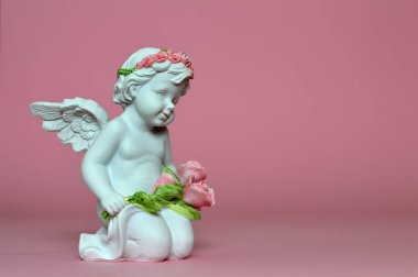Pembe arka planda melek heykeli ve çiçekler   