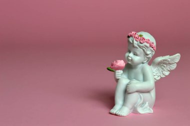 Koruyucu melek pembe arka planda çiçekleri tutuyor.