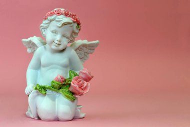 Koruyucu melek pembe arka planda çiçekleri tutuyor.