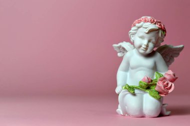 Pembe arka planda çiçekli bir melek heykeli  