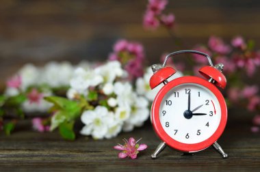 İleri sıçra. Günışığı Tasarruf Zamanı. Kırmızı antika çalar saat ve çiçek çiçekleri.