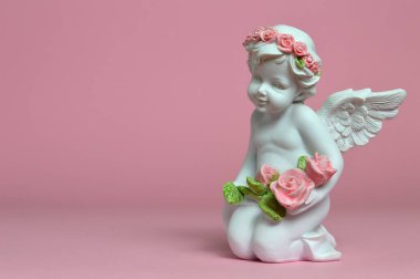 Melek pembe arka planda çiçekleri tutuyor