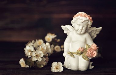 Koruyucu melek ve bahar çiçekleri koyu ahşap arka planda