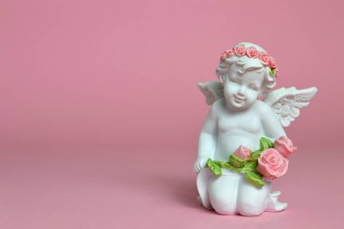 Melek pembe arka planda çiçekleri tutuyor