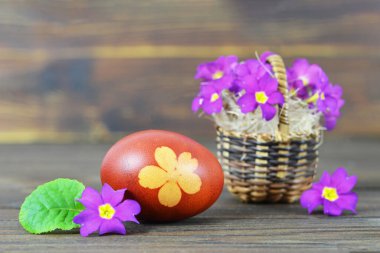 Sepetinde boyanmış yumurta ve bahar çiçekleri olan Paskalya kartı. 