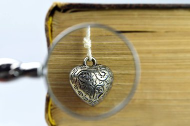 Eski kitap yerine klasik kalp ve büyüteç.