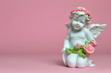 Koruyucu melek pembe arka planda çiçekler tutuyor.