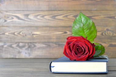 Ahşap arka planda kırmızı gül ve kitap