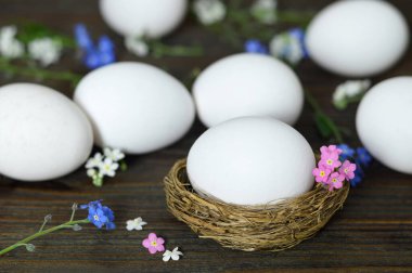  Paskalya yumurtaları ve küçük bahar çiçekleri ahşap masada. 