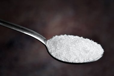 Kaşık içindeki şeker tozunu koyu arkaplanda kapat
