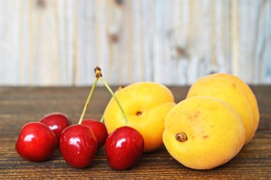 Tahta masada taze kayısılar ve kirazlar.