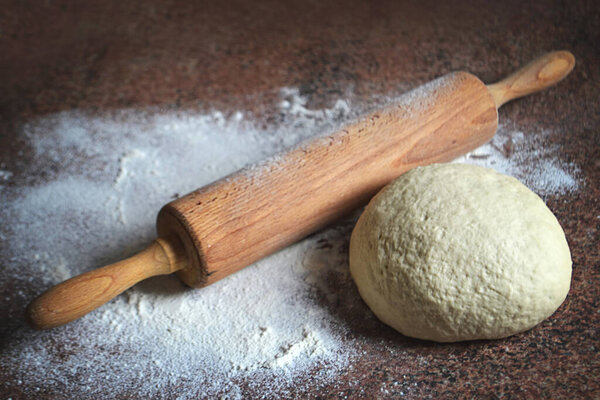 Homemade dough and rolling pin on kitchen board