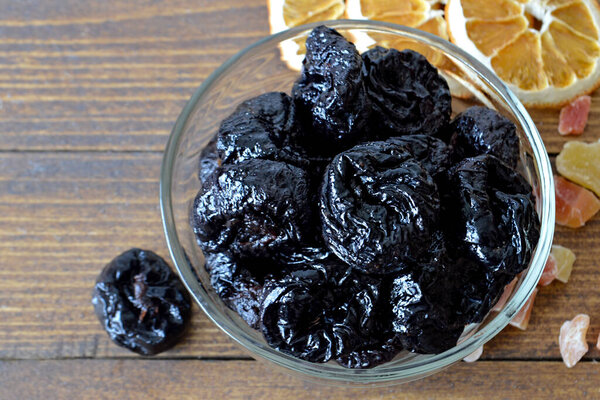 black dried plums on a wooden background