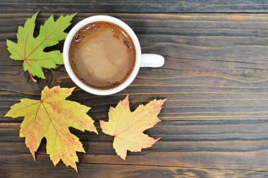 Sonbahar kompozisyonu. Bir fincan kahve ve sonbahar yaprakları ahşap arka planda