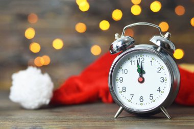 Noel Baba şapkalı çalar saat bulanık Noel ışıklarına karşı, yakın plan. yeni yıl geri sayımı