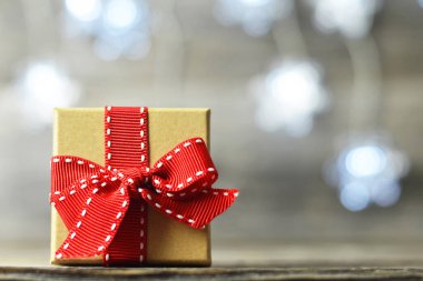 Tahta bir masada kurdeleli hediye kutusuyla noel kartı.