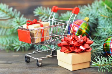 Noel alışveriş arabası ve ahşap arka planda hediyeler
