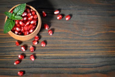 Tahta zemin üzerinde bir kasede taze nar tohumları.