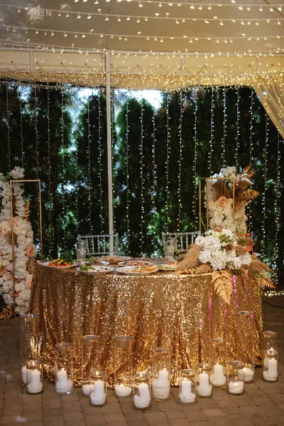 餐厅宴会厅里的新婚夫妇主席团装饰着蜡烛和绿色的植物 天花板上挂着紫藤 — 图库照片