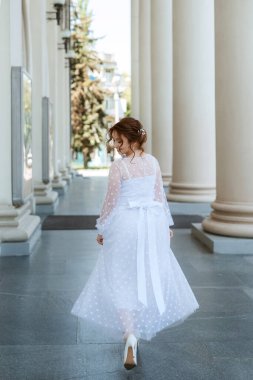 portrait of a young bride girl in a light dress walks in an urban environment
