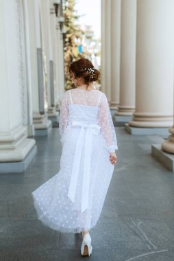 portrait of a young bride girl in a light dress walks in an urban environment