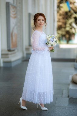 portrait of a young bride girl in a light dress walks in an urban environment