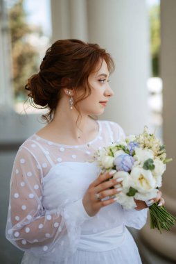 portrait of a young bride girl in a light dress walks in an urban environment